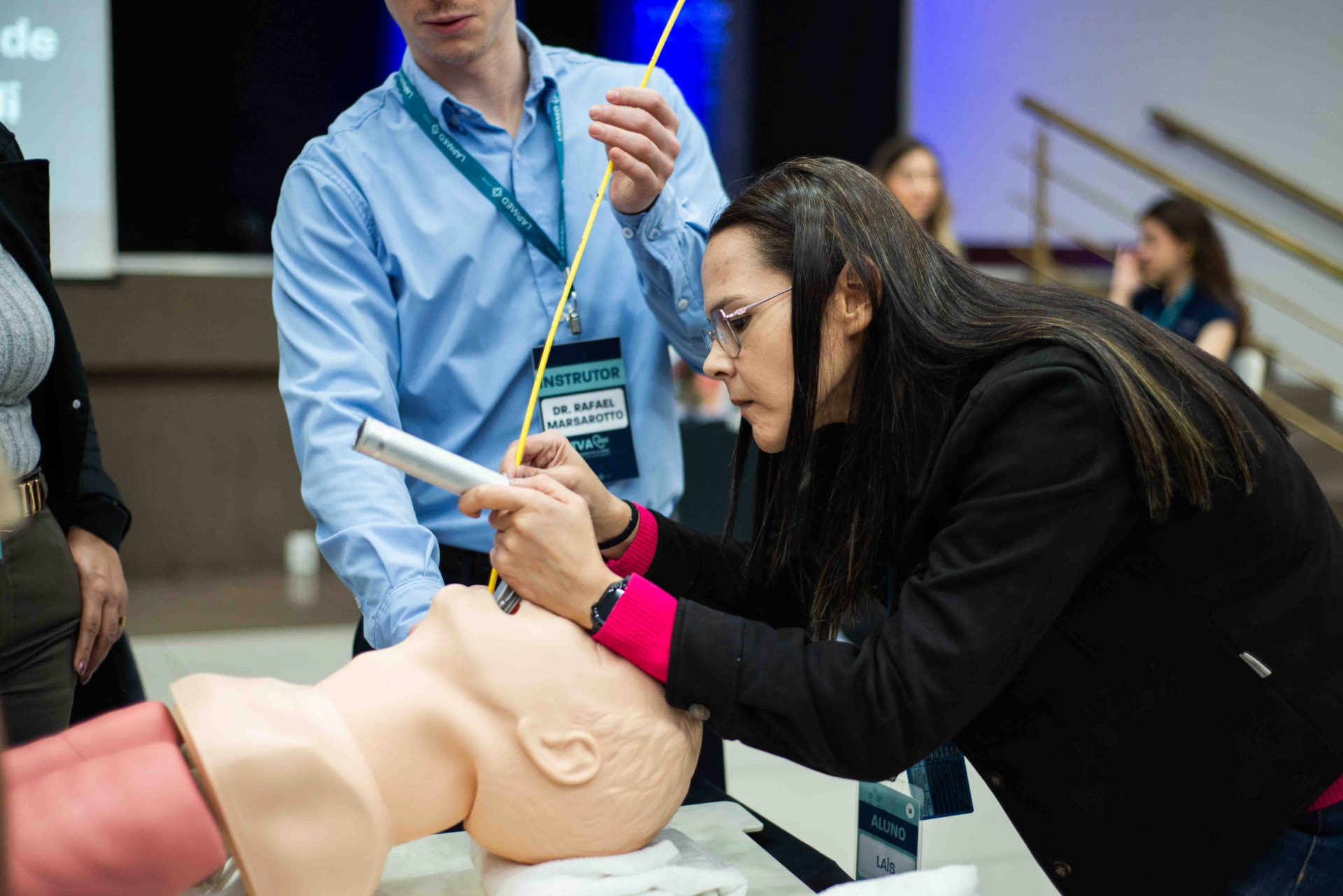 Médica treinando intubação em manequim com orientação do instrutor durante o TVA360